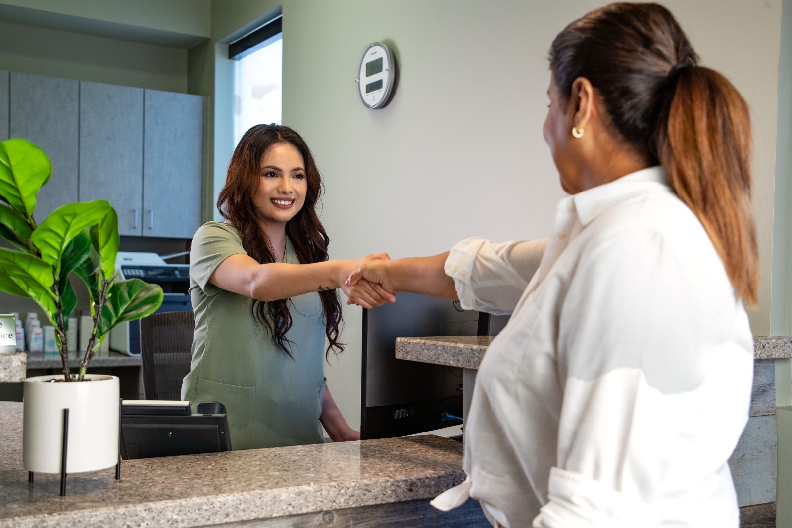 A dental assistant shaking hands with a new patient