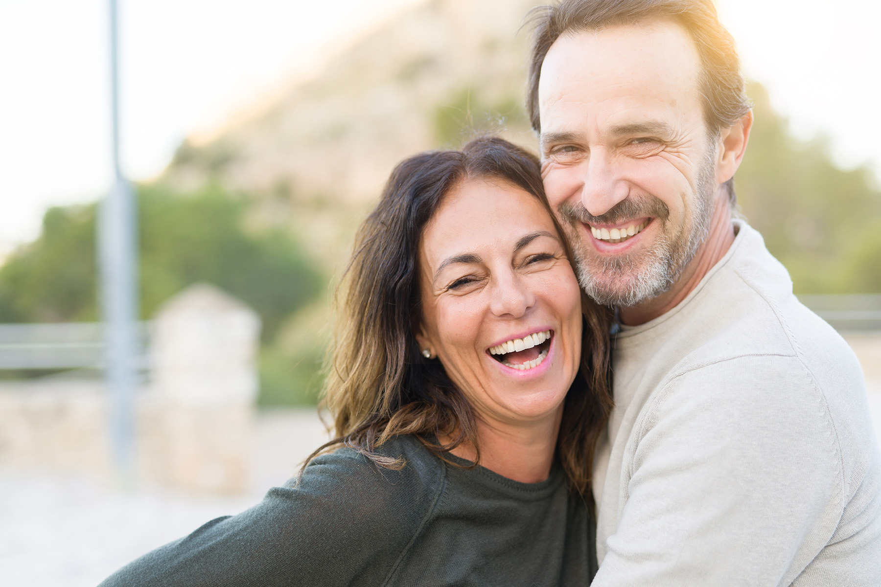 Romantic couple smiling and cuddling on a sunny day